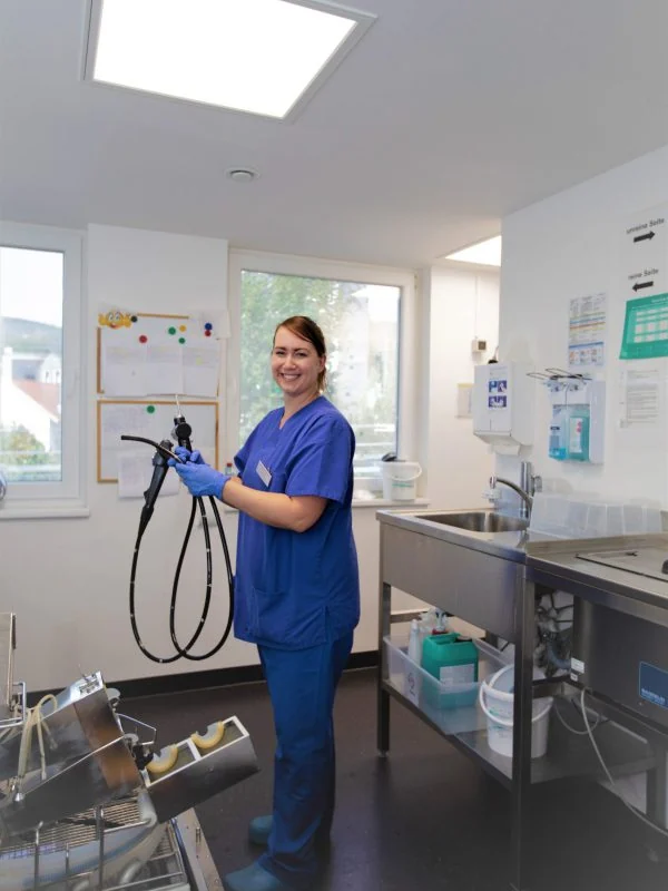 Mitarbeiterin mit einem Endoskop im Aufbereitungsraum