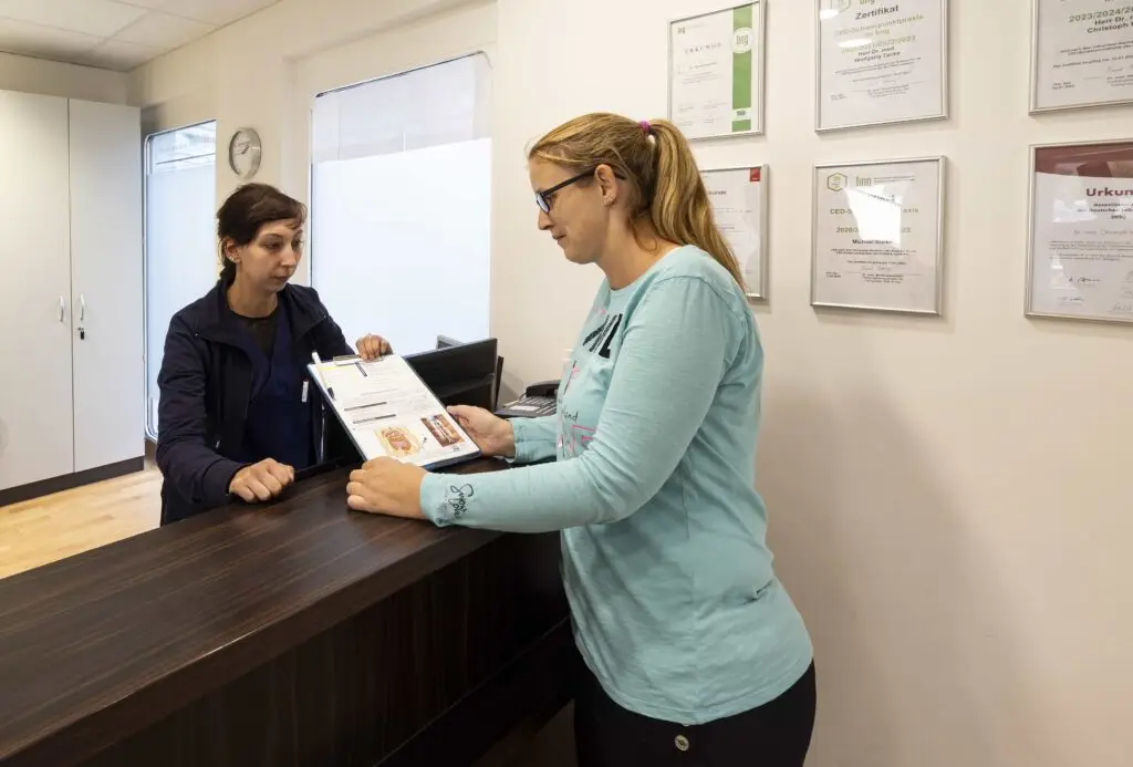 Mitarbeiterin bespricht Unterlagen mit einer Patientin